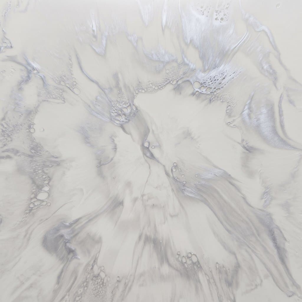 The same silver metallic epoxy floor over a pale gray base color, the pattern only just readable against the light ground