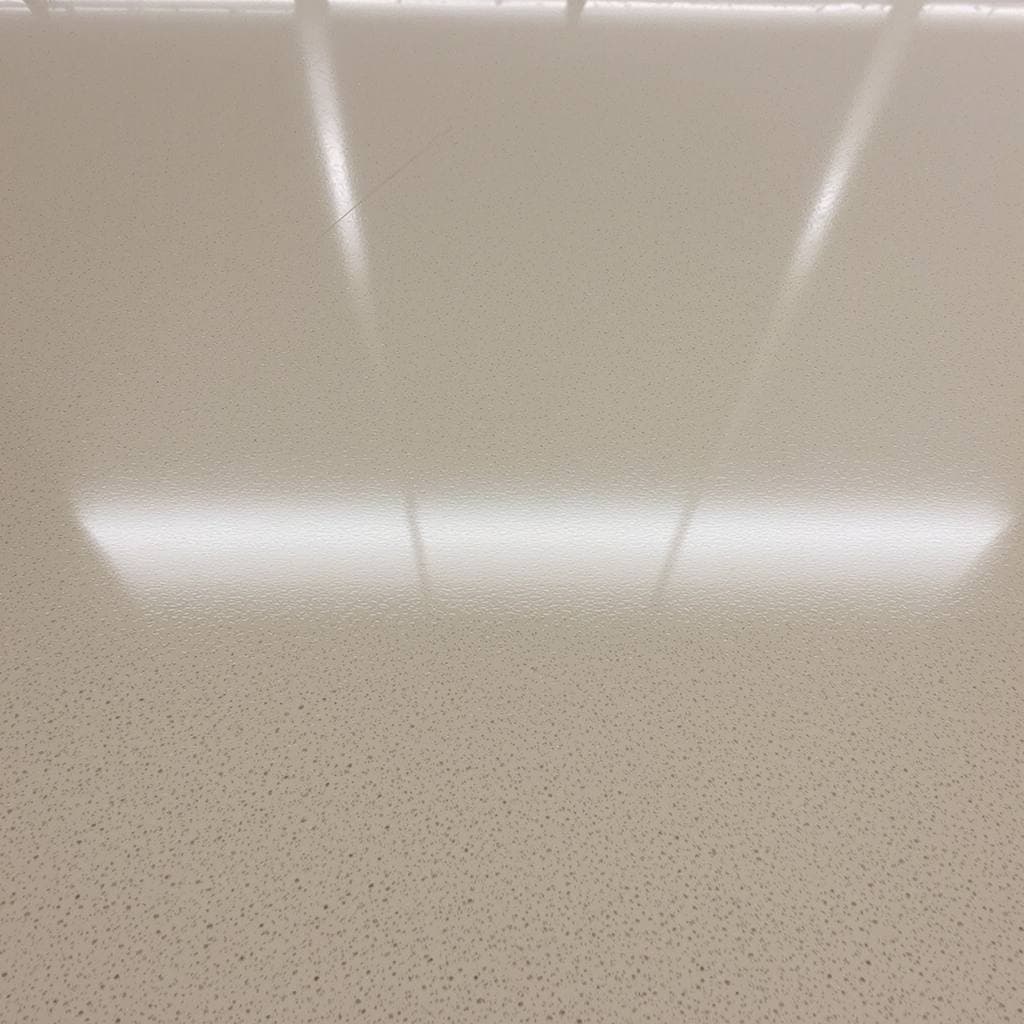 A highly polished concrete floor seen at a low angle, the overhead lighting reflecting off it in sharp bright bands running away from the camera