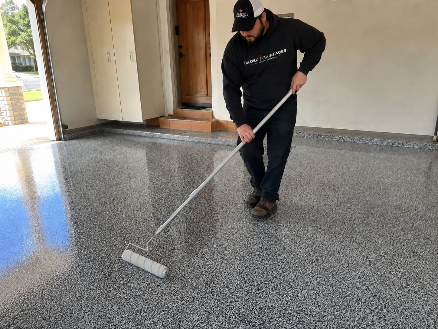 Gilded Surfaces crew member rolling the clear coat over a finished grey flake floor