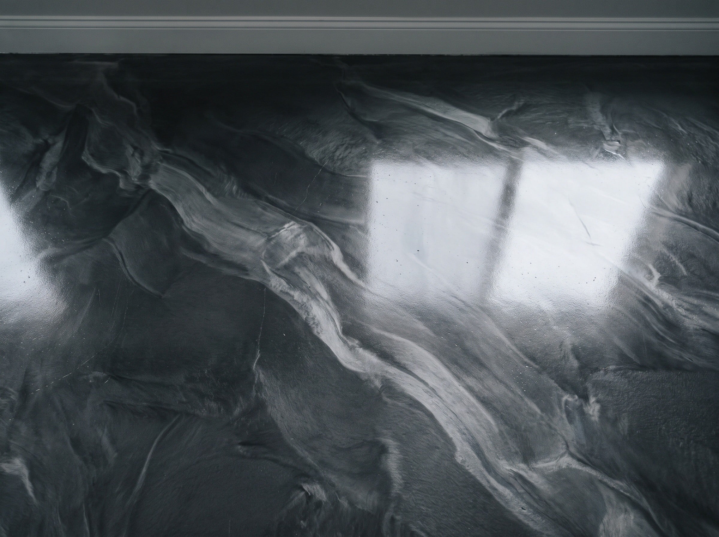 Top-down detail of a charcoal and silver metallic epoxy floor, about half a square meter, in daylight