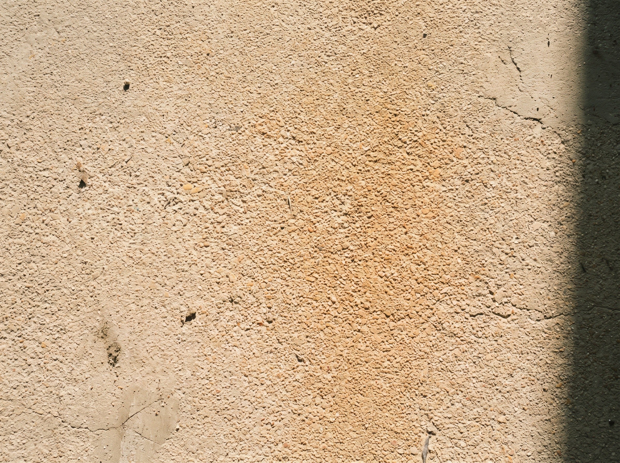 Top-down detail of a sand-colored quartz broadcast floor, about half a square meter, in daylight