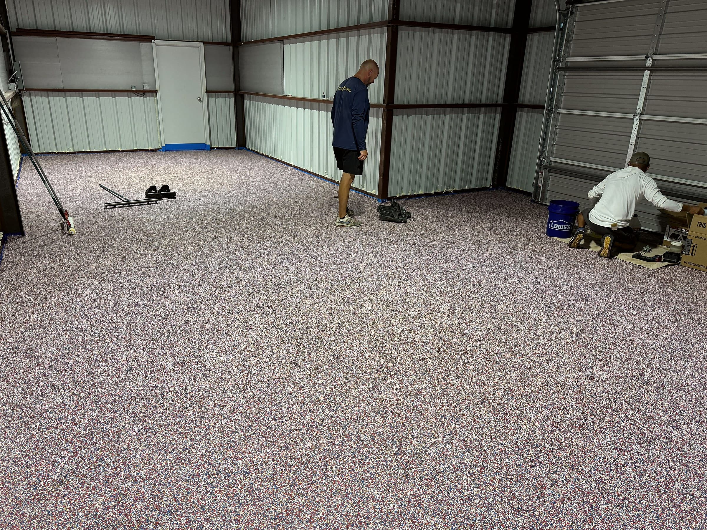 Gilded Surfaces crew on a freshly broadcast floor in a steel building
